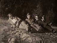Zwei Zivilmänner und in der Mitte ein Soldat 