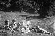 Frau mit fünf Kindern während einer Wiesenrast. 