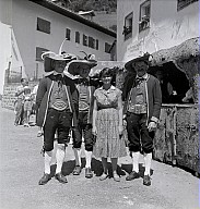Ein Dorffest: Eine Frau und drei in Tracht gekleideten Männer 