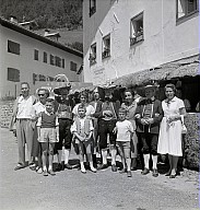 Ein Dorffest: Gruppenbild mit Frauen, Männer und Kinder, einige in der Tracht. 