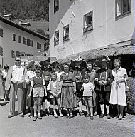 Ein Dorffest: Gruppenbild mit Frauen, Männer und Kinder, einige in der Tracht. 