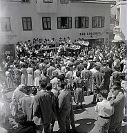 Ein Dorffest: Konzert der Musikkapelle, im Vordergrund eine Menschenmenge. 
