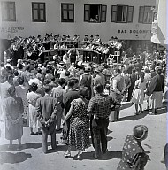 Ein Dorffest: Konzert der Musikkapelle, im Vordergrund eine Menschenmenge. 