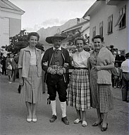 Ein Dorffest: Drei Frauen und ein in Tracht gekleideter Herr. 