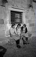 Drei Mädchen sitzen vor der Kirche Sankt Georg am Kofel. 