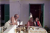 Personengruppe in sommerlicher Kleidung auf der Terrasse eines Hauses. 