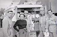 33. Giro d'Italia: Eine Gruppe Männer und eine Frau vor den geöffneten Türen eines Auto, in dem Säckchen mit der Aufschrift "Nestlè" transportiert werden. 