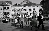 Ein folkloristischer Umzug: Frauen und Männer in traditioneller Kleidung führen auf dem Platz einen Volkstanz vor. 