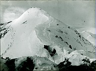 Zwei Soldaten am Eingang eines Eisstollens unterhalb einer verschneiten Bergspitze 