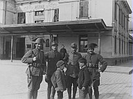 Quattro soldati e due bambini davanti alla stazione ferroviaria