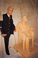 Silvius Magnago vicino alla scultura in legno che lo raffigura seduto